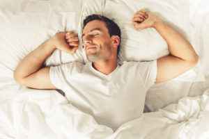 man stretching waking up from good night sleep